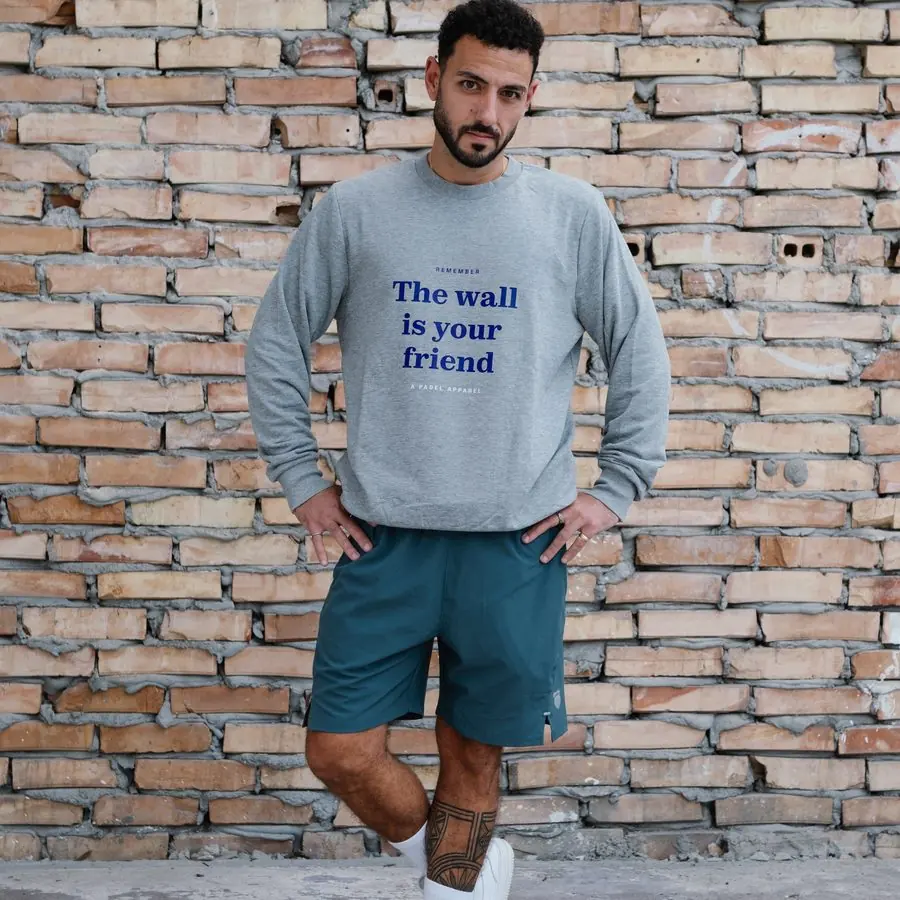 The wall is your friend crewneck against a brick wall